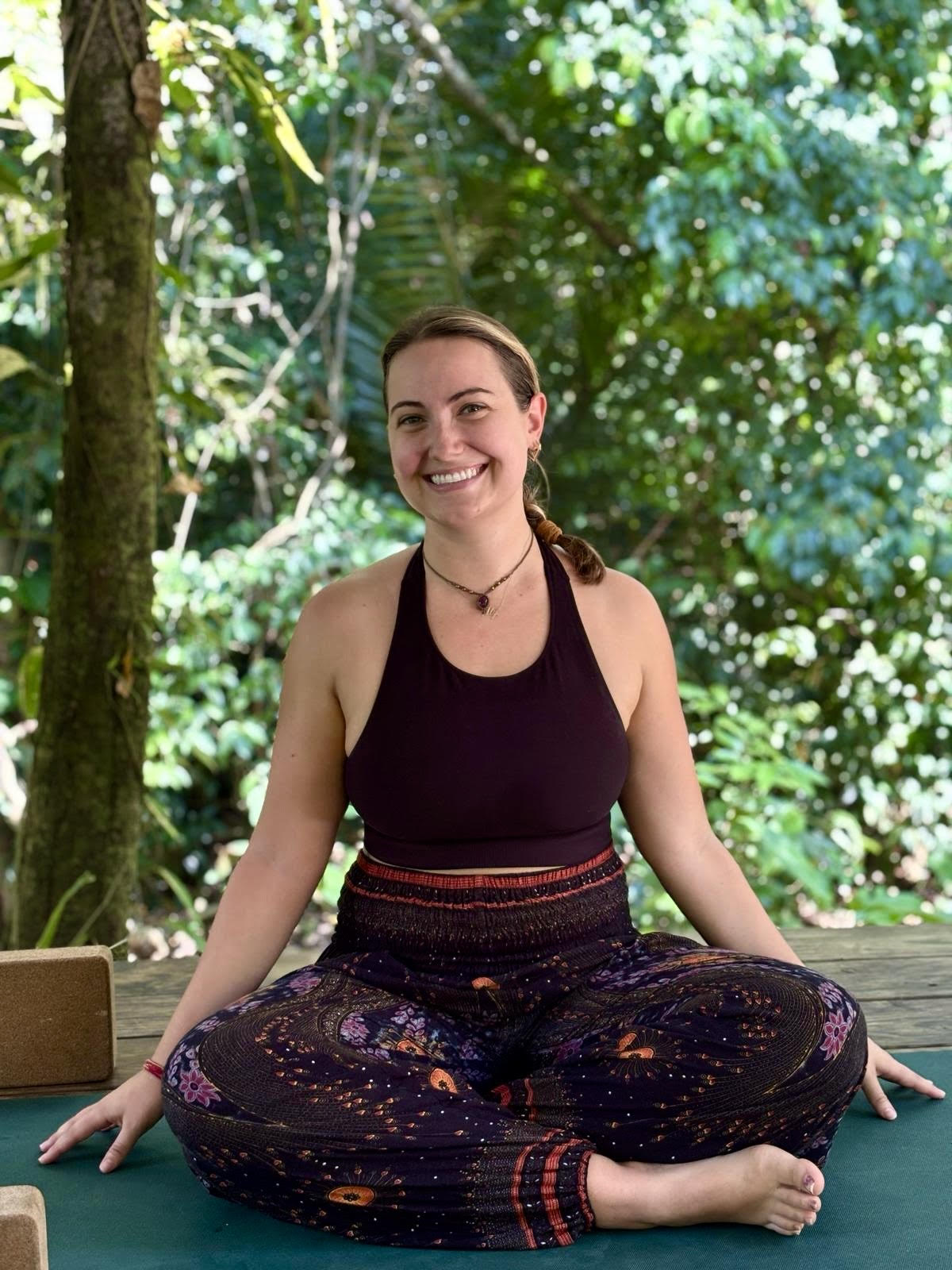 Ally sitting cross-legged on a yoga mat in Costa Rica